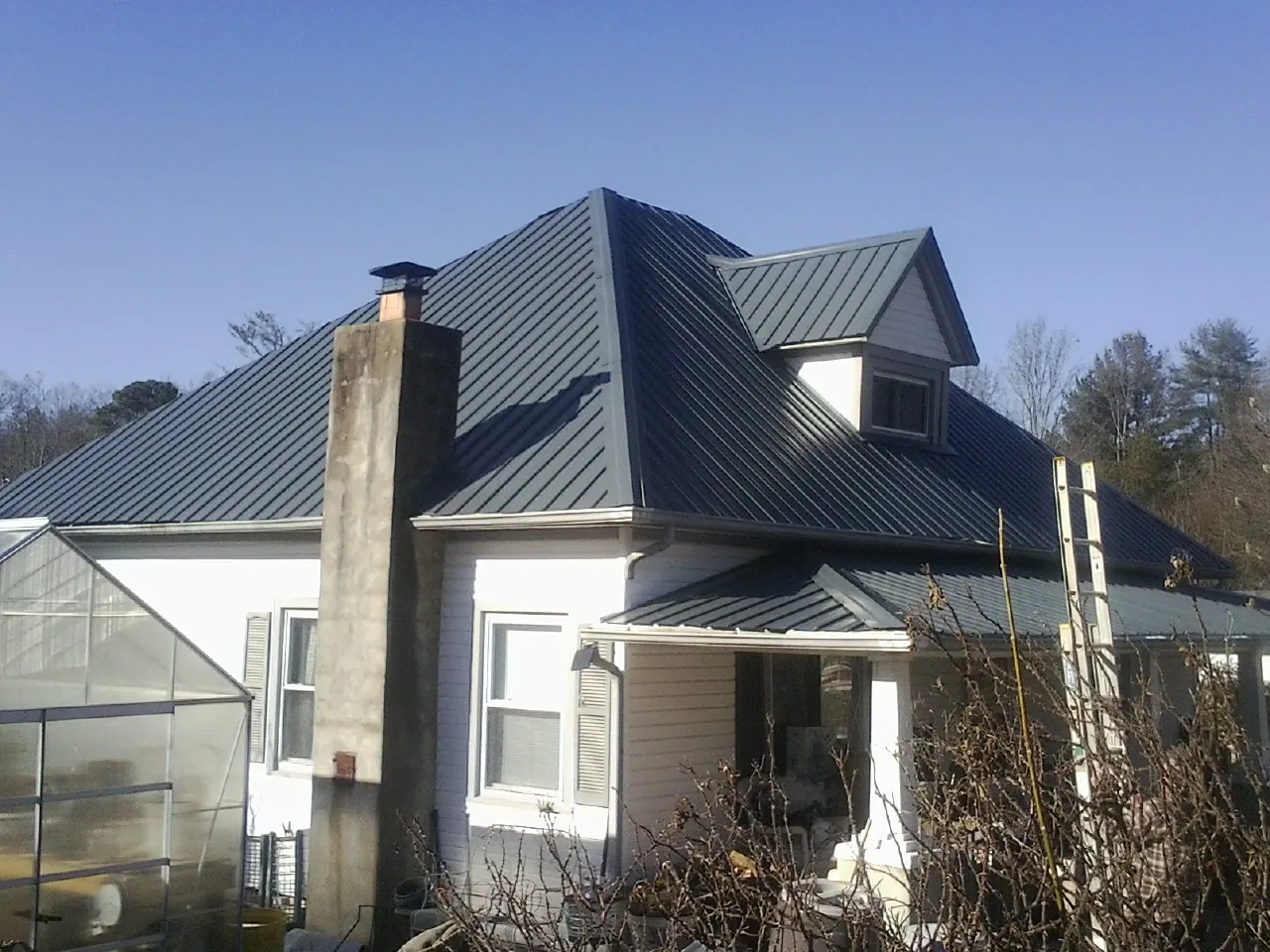 Dark blue standing seam metal roof on a white farmhouse with dormer — Slate & Tile Roof Repair by Roofing Brothers in Wernersville