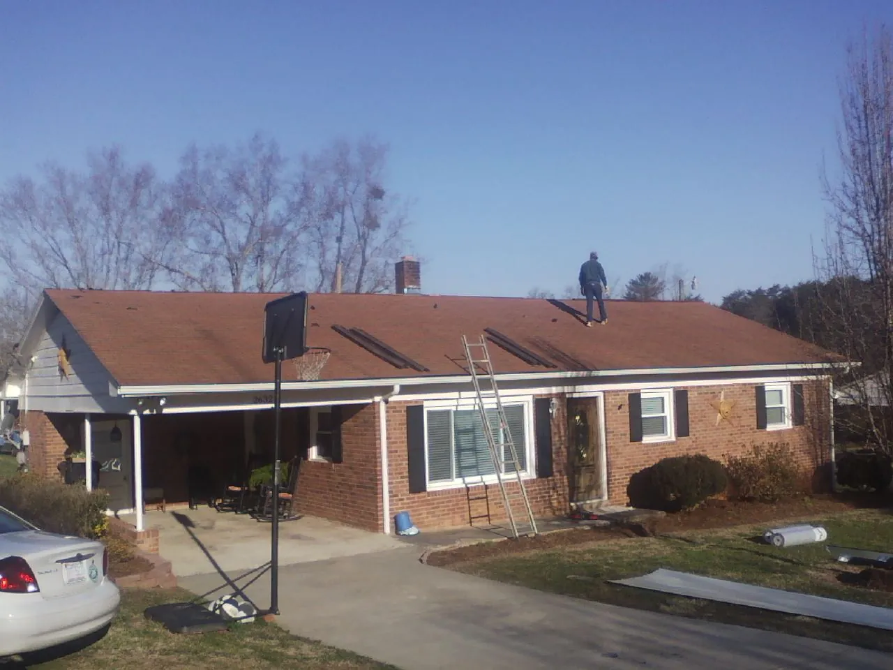Roofer stripping a shingle roof on a brick ranch before metal panels in Wernersville