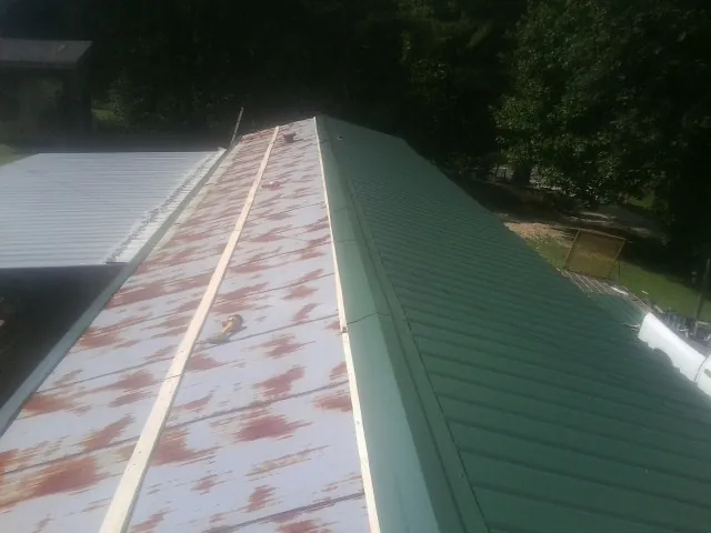 Old rusted panels beside newly installed green metal roofing — Wind Damage Roof Repair by Roofing Brothers in Wernersville