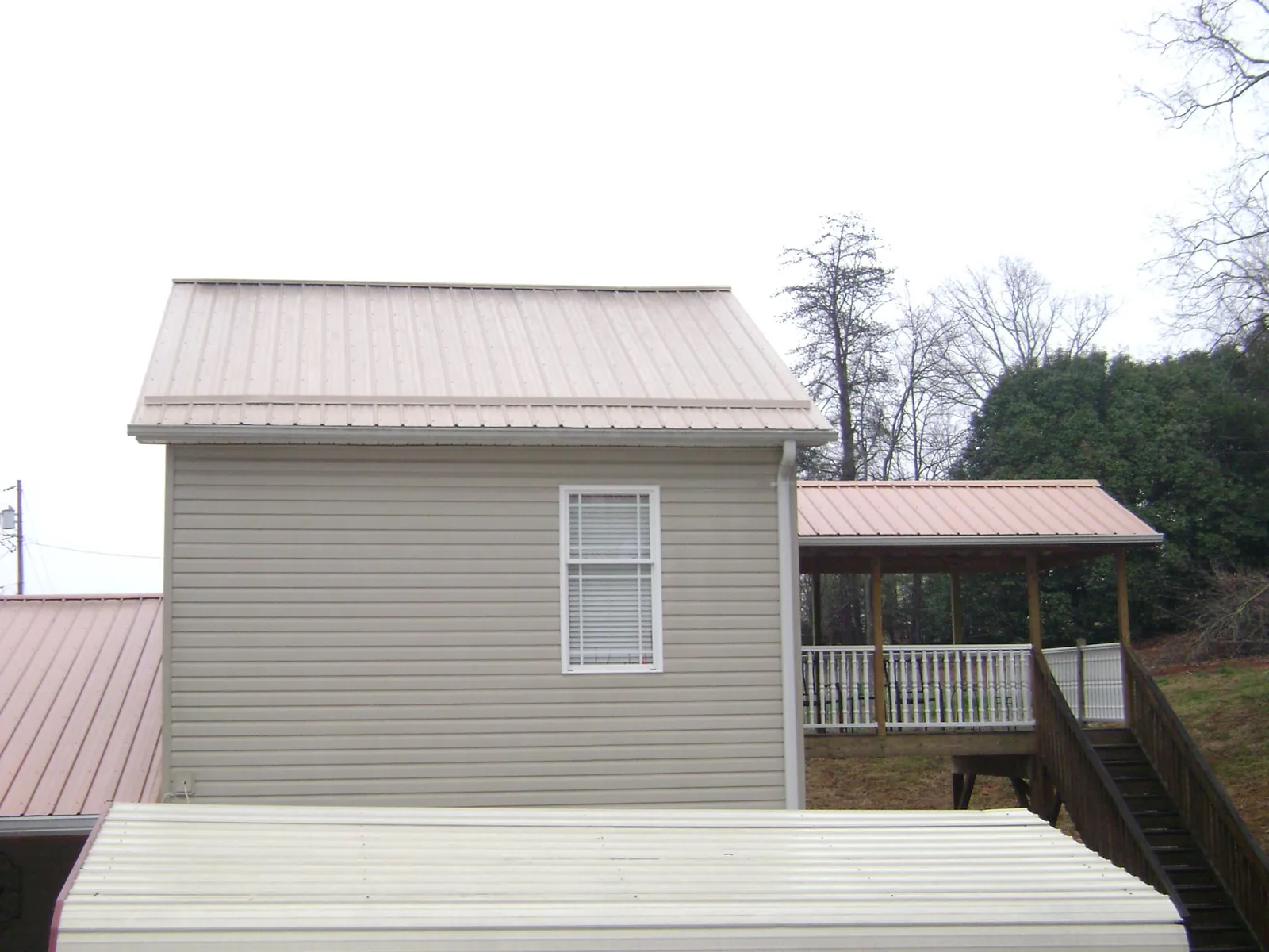 Tan metal roofs on a two story addition and attached porch, from a Roof Replacement job in Wernersville