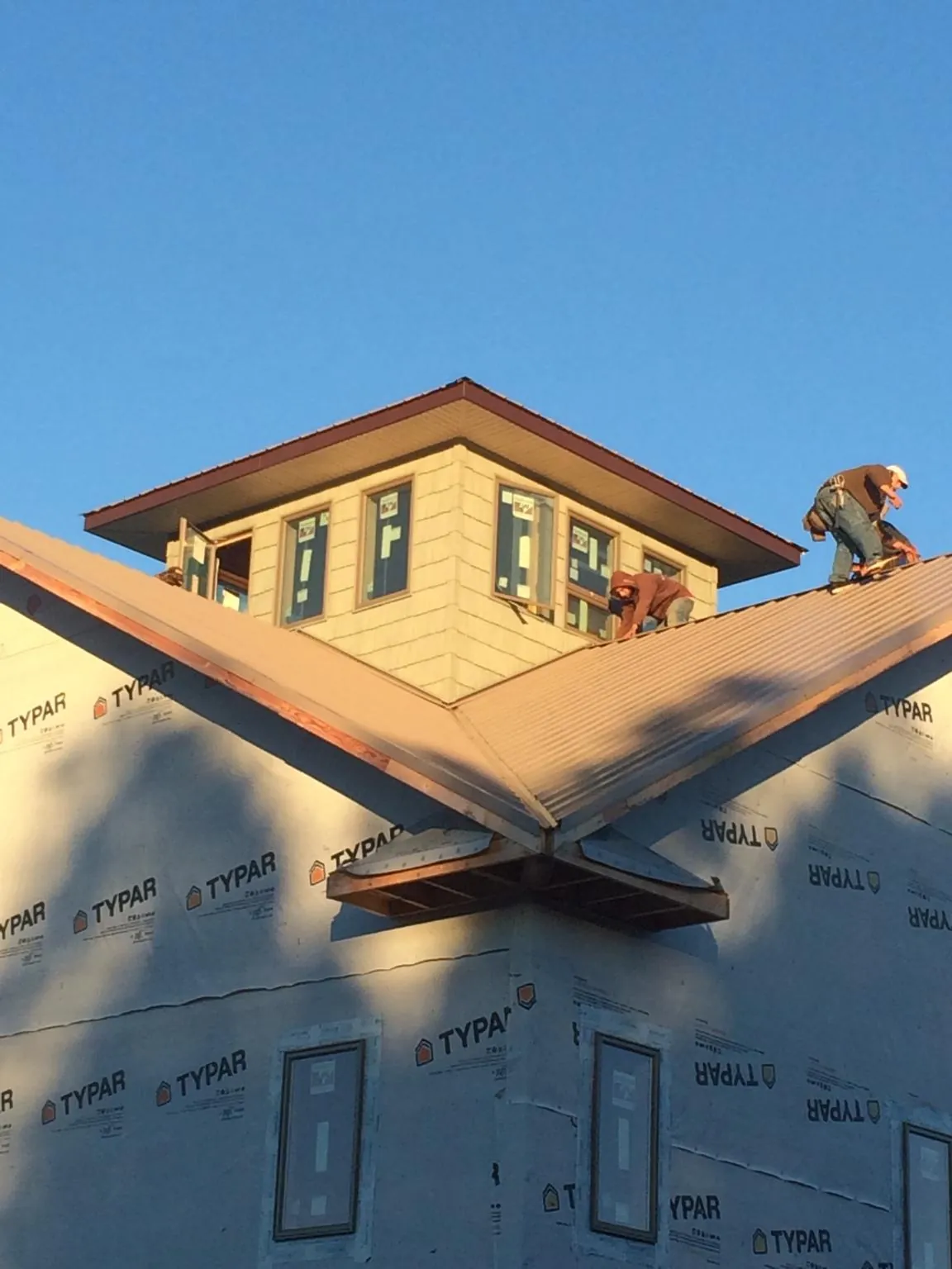 Roofers working around a rooftop cupola on a new metal roof at sunset — Roof Waterproofing in Wernersville by Roofing Brothers